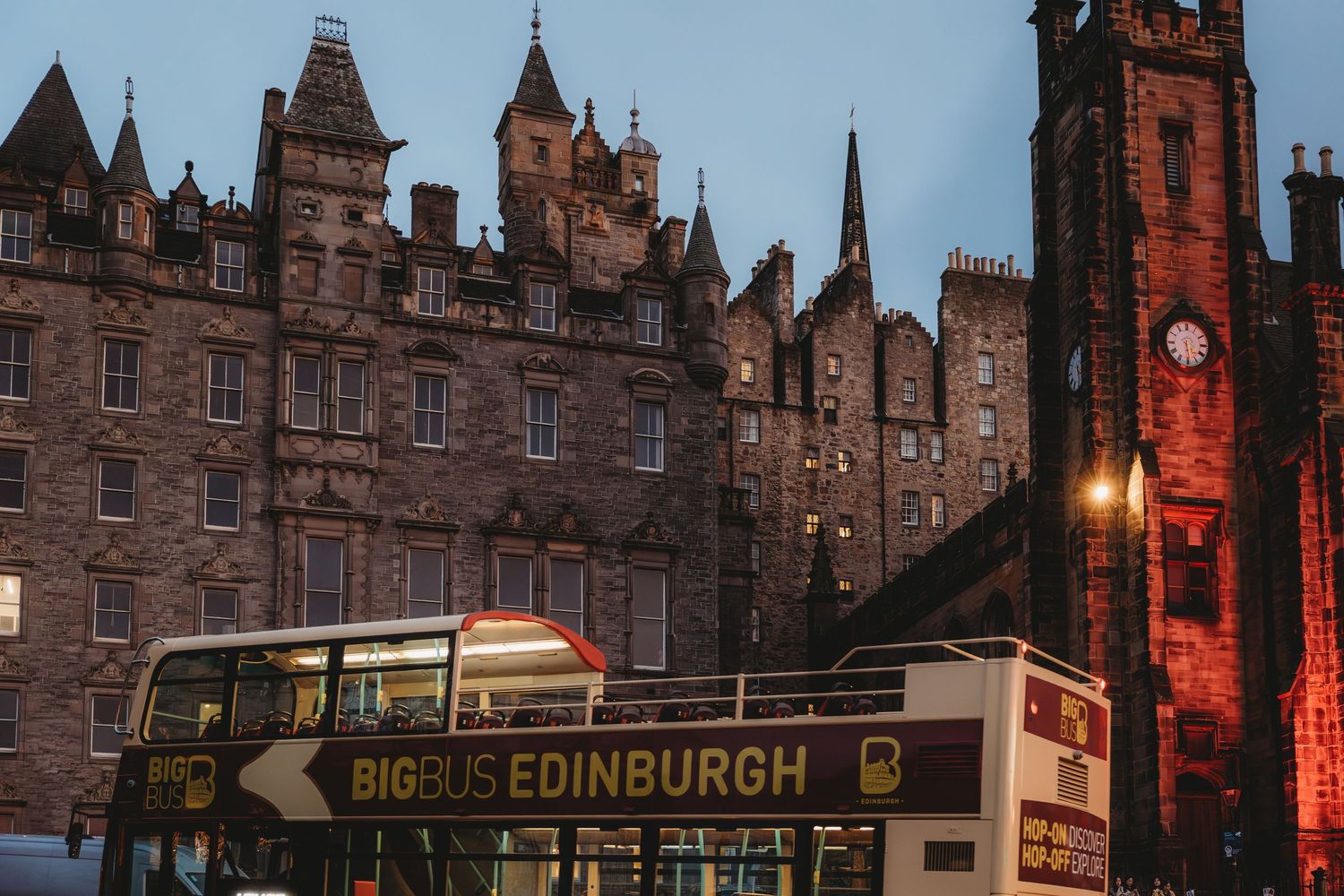Historic buildings along the Royal Mile in Edinburgh illuminate the evening skyline with warm lighting and gothic architecture.