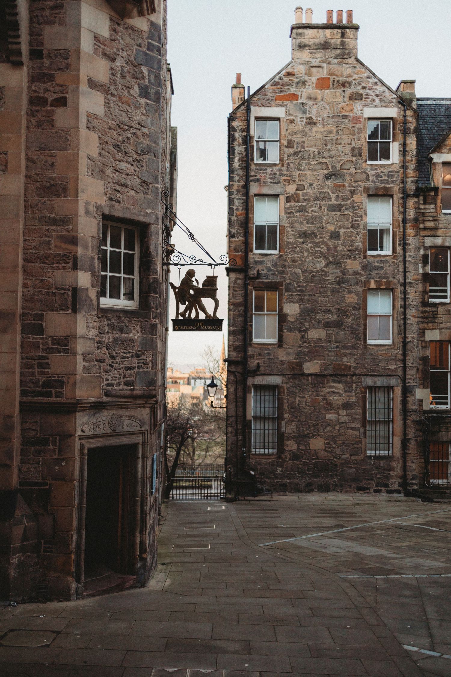 Stone buildings with windows and cobblestone walkways in Edinburgh's historic Old Town at dusk.