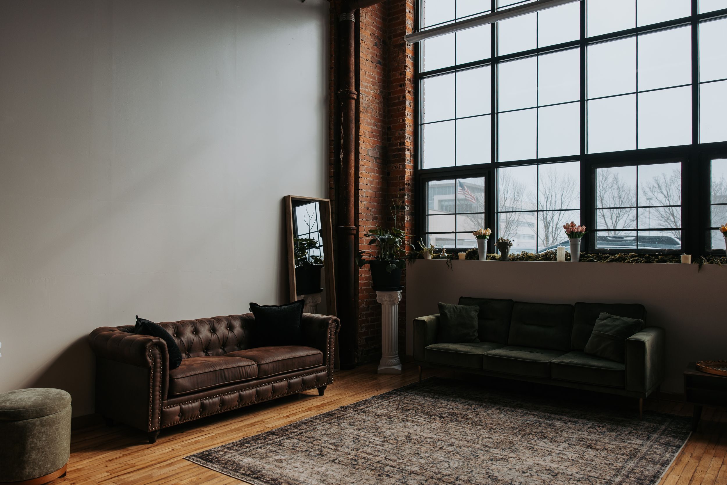 Modern living room interior with large windows, leather sofa, and industrial style decor in panoramic view.