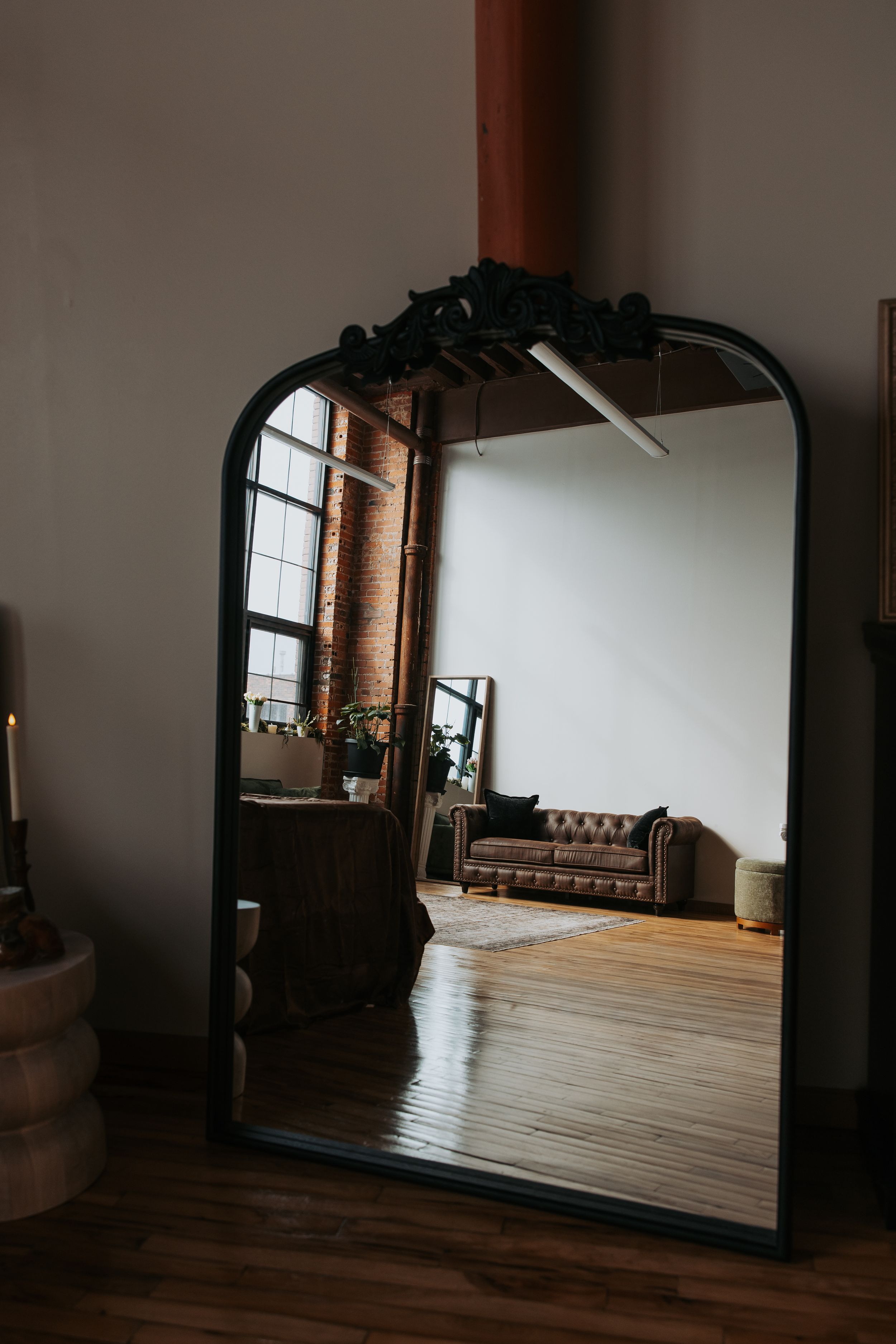 Moody interior shots of a loft space with exposed brick walls, wooden floors, and leather furniture in dim lighting.