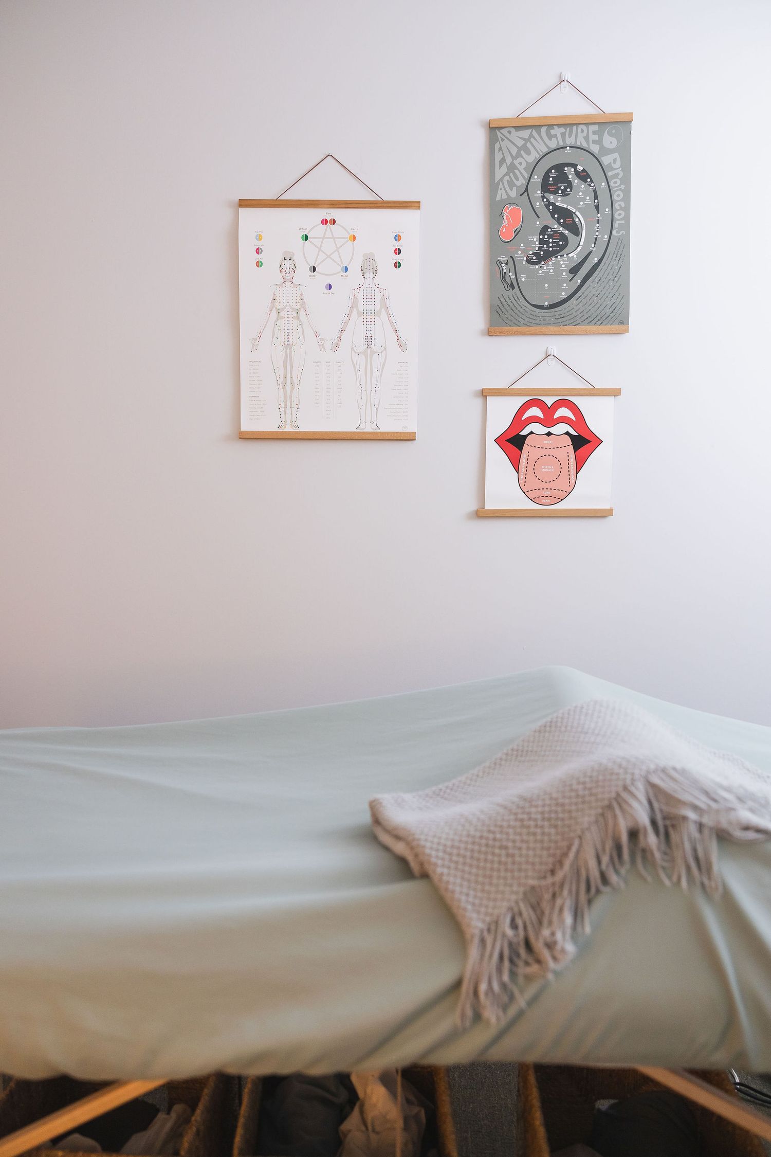 Maple Valley Acupuncture, WA branding photo of treatment room of acupuncturist clinic with table & blankets and acupuncture posters on wall
