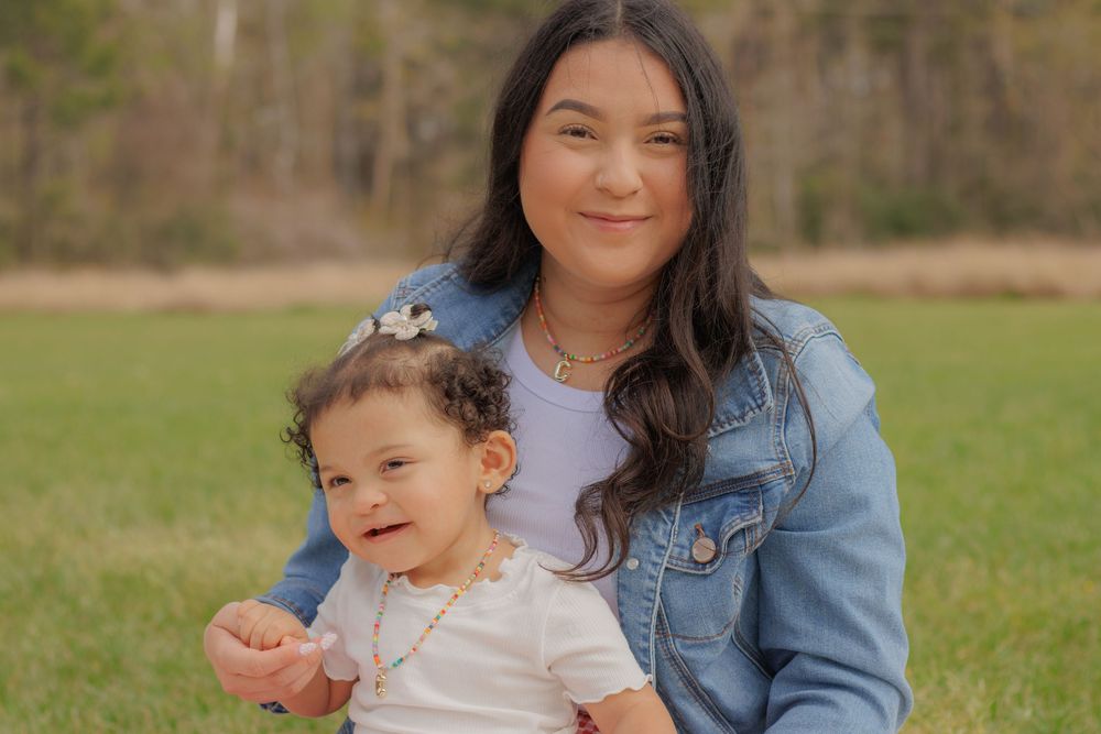 A tender moment captured outdoors with a denim jacket and joyful expressions in a natural setting.