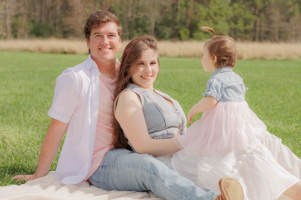 Family photoshoot in a meadow with coordinated pastel and white outfits.