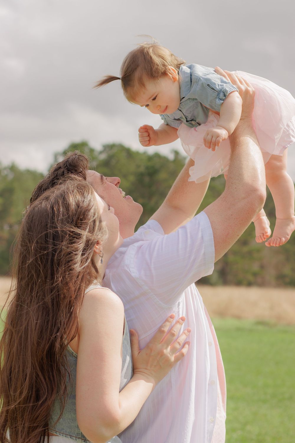 Playful outdoor family photos with white dress against a natural backdrop.