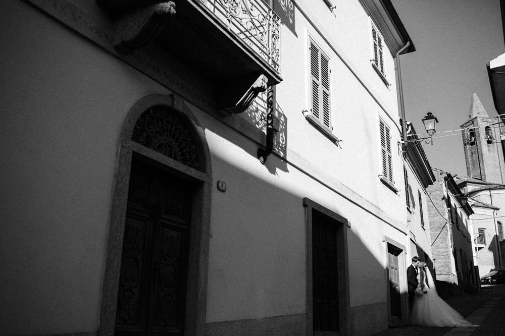 black and white image of wedding couple kissing in the streets of Mombaruzzo