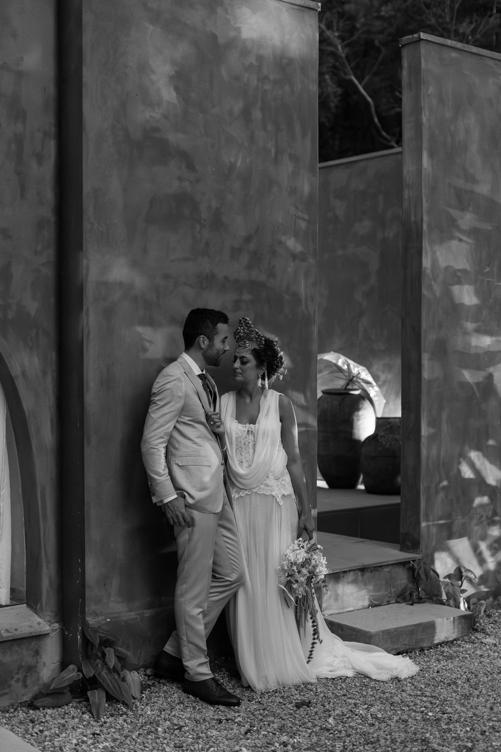 A romantic black and white wedding photo series showing a couple embracing against a textured wall.