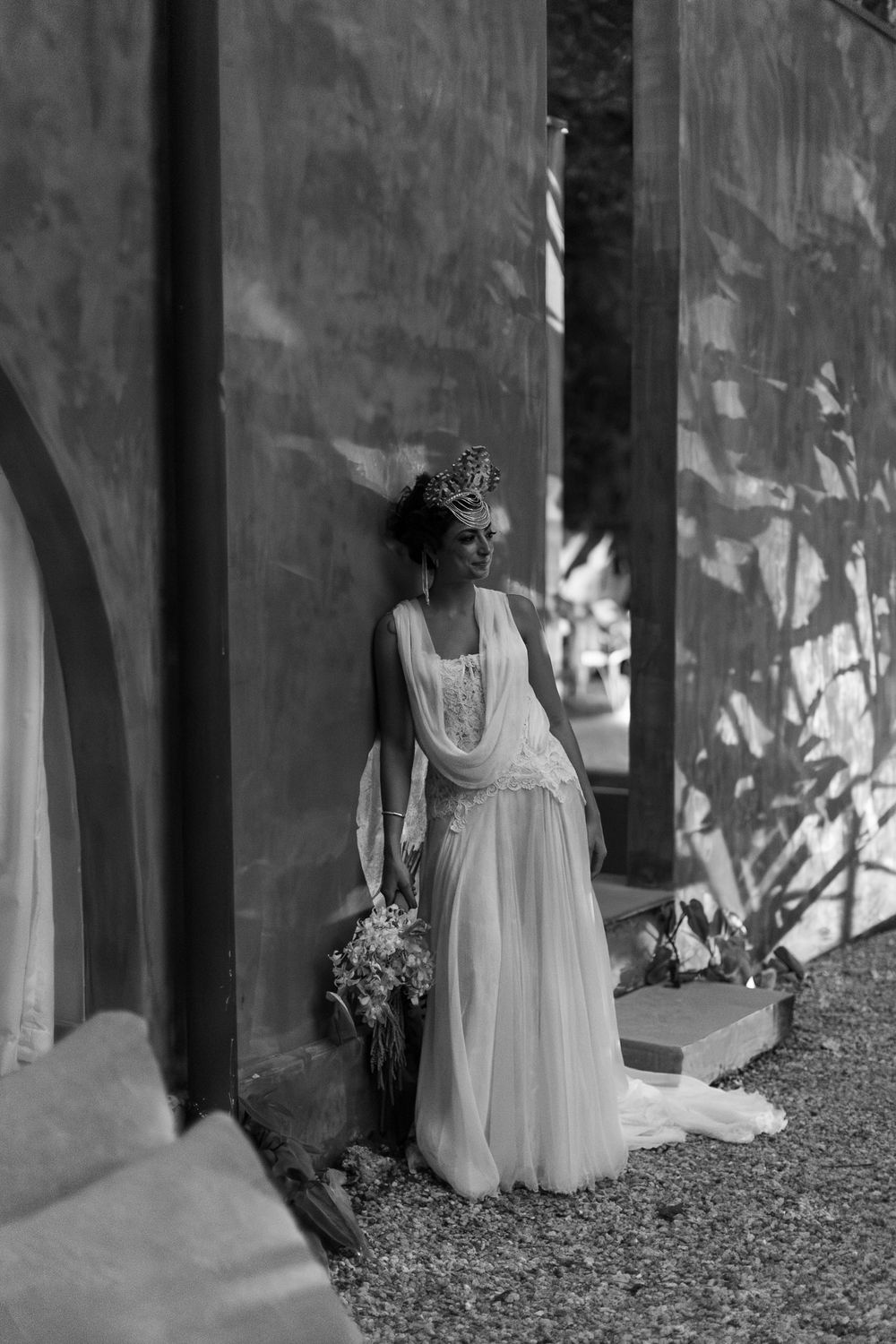 A sequence of black and white photos showing a person in a flowing white dress walking through a shaded outdoor corridor.