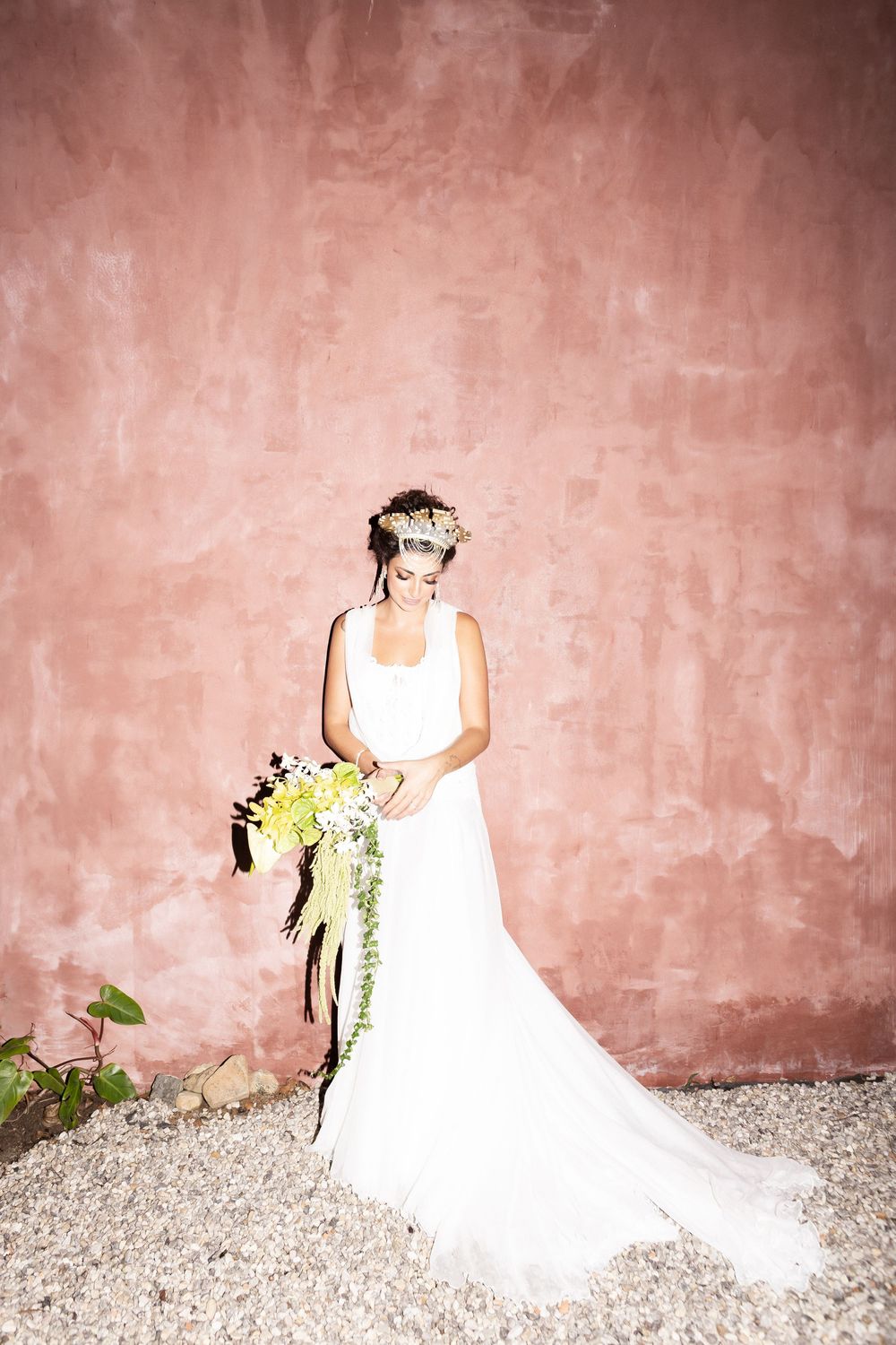 A series of wedding photos showing a bride in a white gown against a pink textured wall and gravel ground.