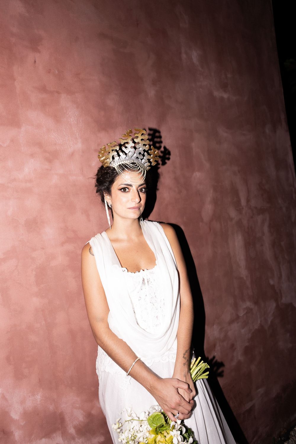 A person in a white sleeveless dress poses against a pink stucco wall in varying artistic shots.