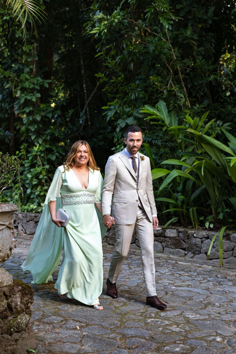 Couple walking along a stone path surrounded by lush tropical gardens.