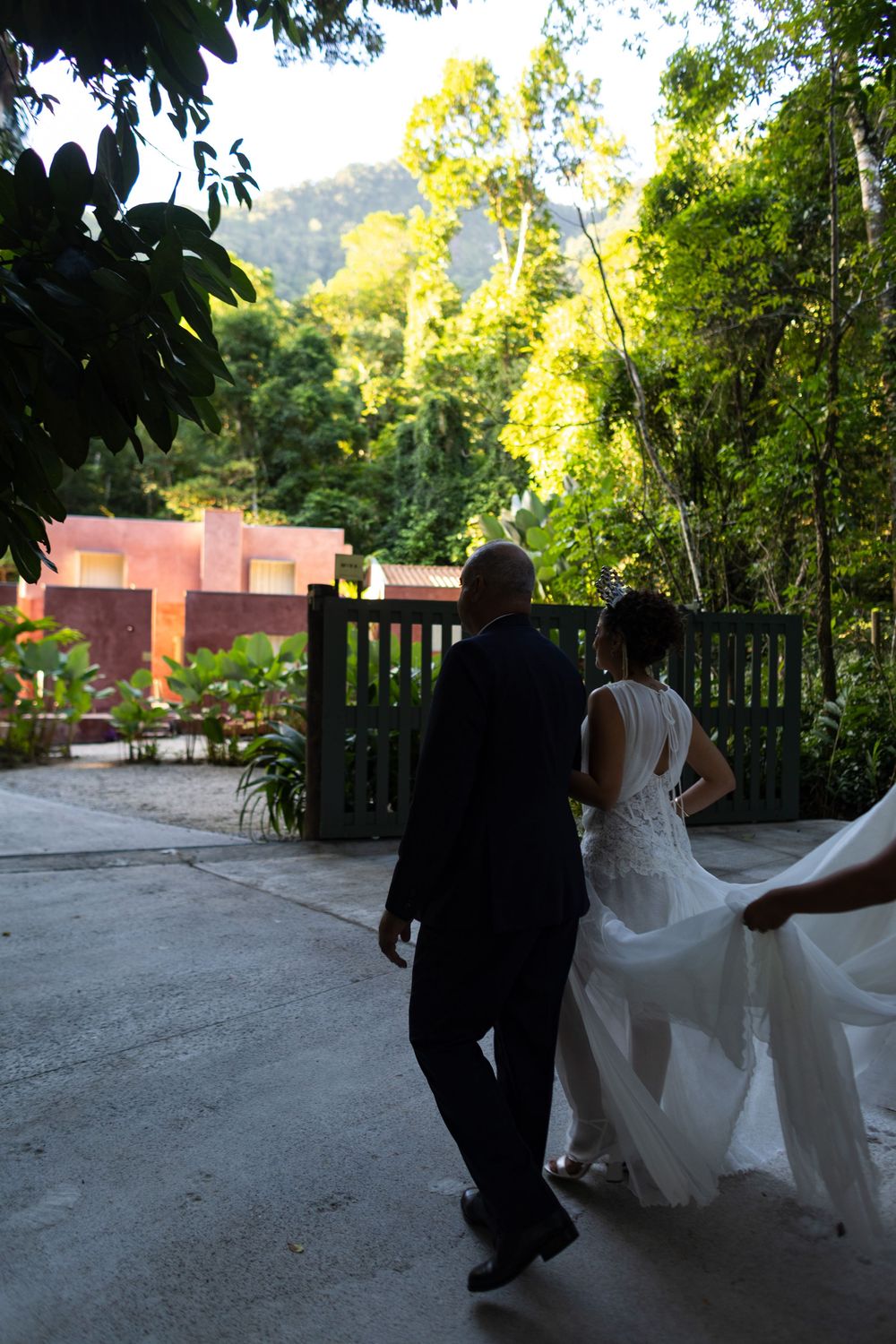 Wedding couple walking along a tree-lined path with dramatic lighting.