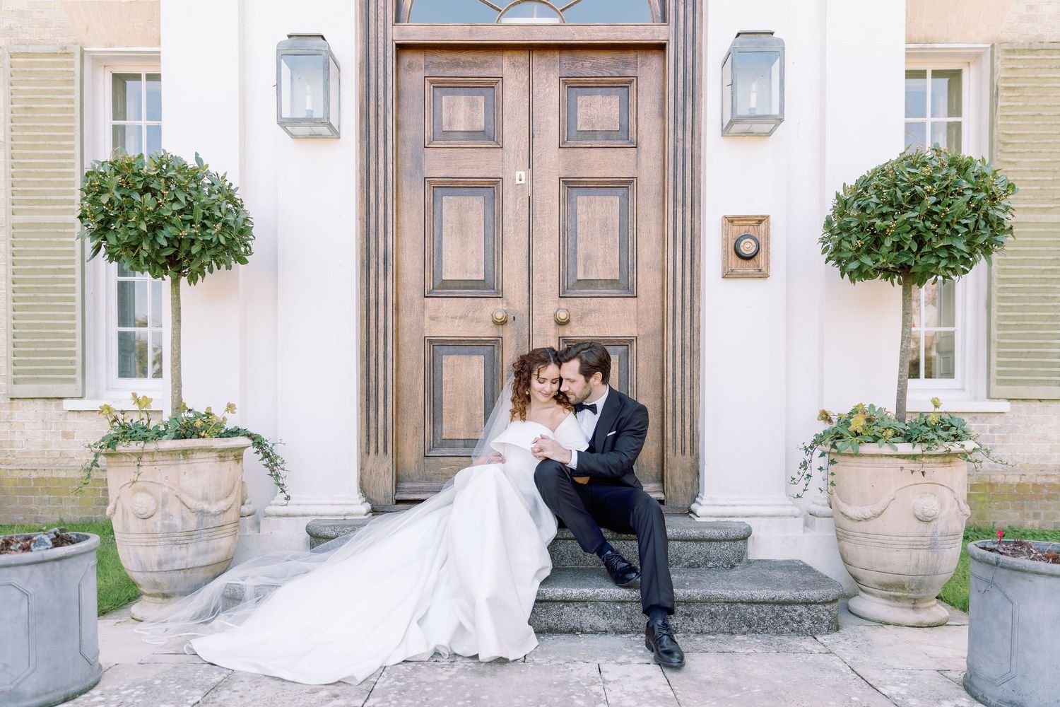 A romantic wedding photo sequence showing a couple in formal attire posing against an elegant stone building entrance.