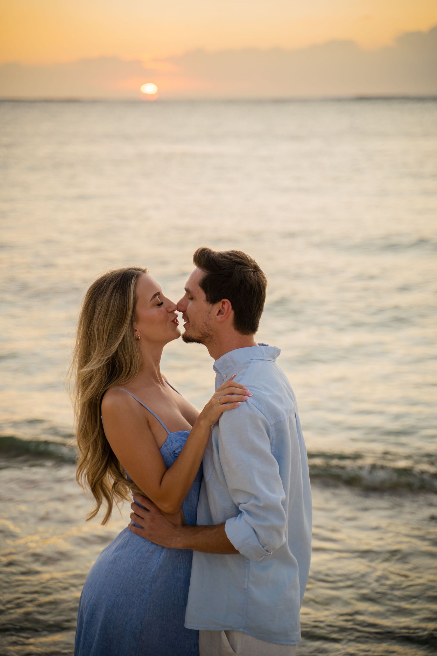 Romantic beach photoshoot at sunset with ocean backdrop.