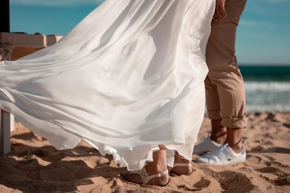 Detailaufnahme: Das Brautkleid weht im Wind am Strand. Ein sinnlicher Moment während der Hochzeitsreportage.