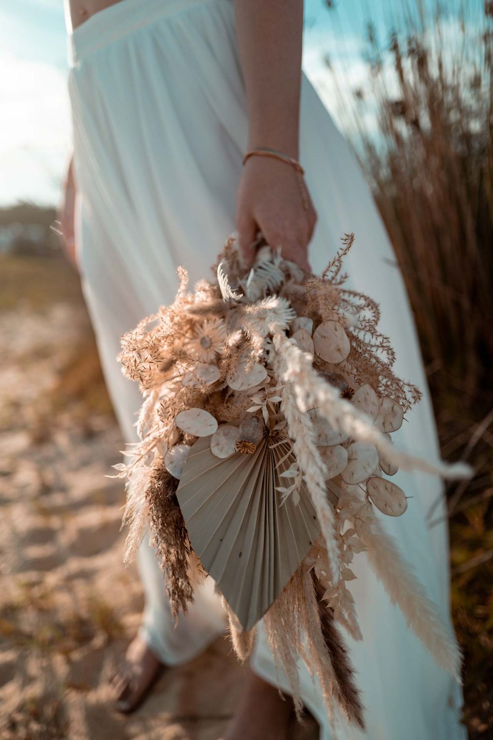 Nahaufnahme eines herbstlichen Brautstraußes aus Trockenblumen am Strand. Fokus auf Texturen und Natur
