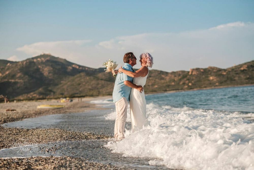 Brautpaar küsst sich innig im seichten Wasser am Strand. Romantische Stimmung bei Sonnenuntergang