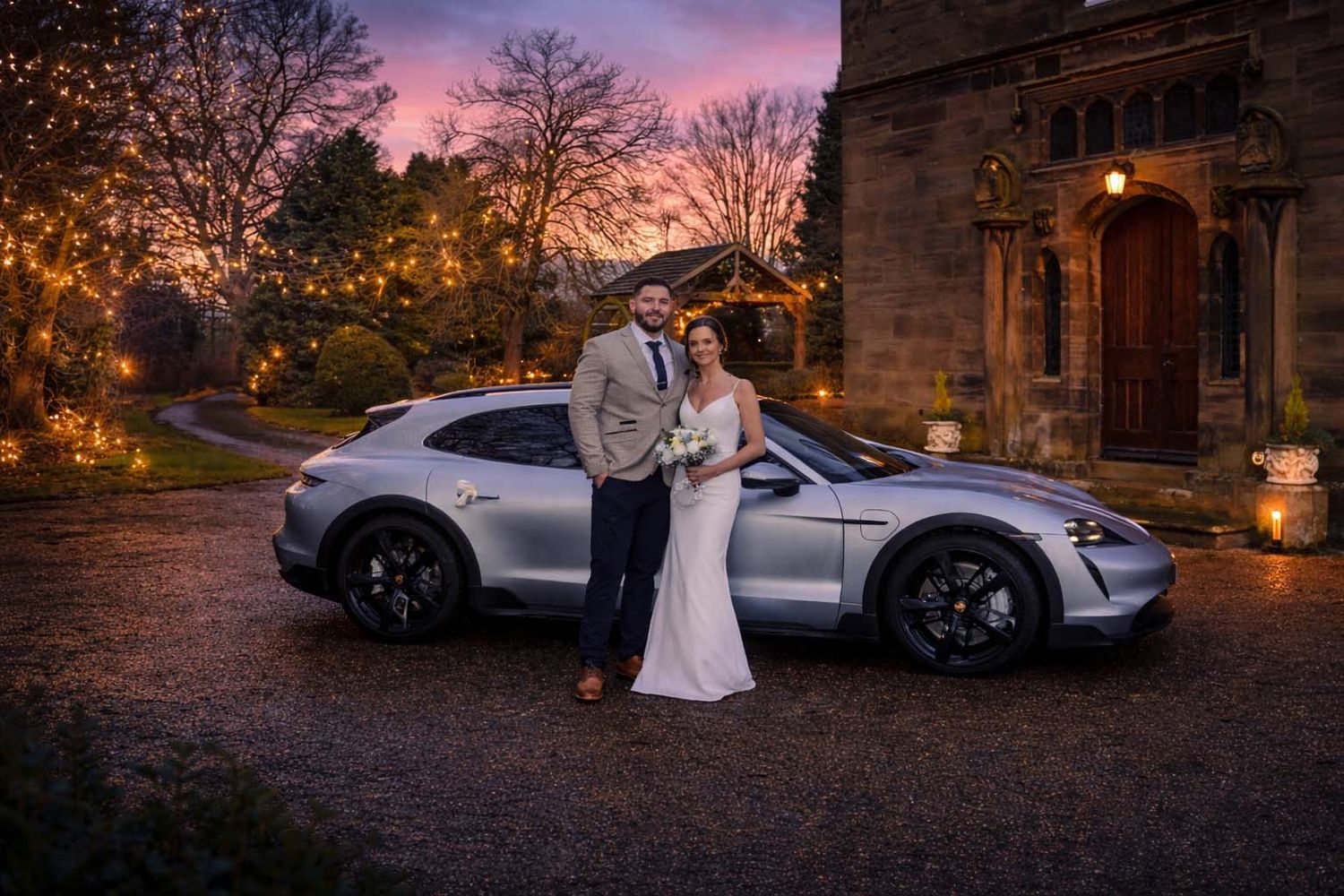 A luxury sports car parked at a stone building during sunset creates a romantic ambiance at dusk.