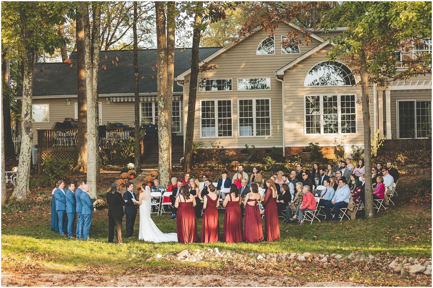 Large group of people gathered outside a residential building for a group photo shoot on a sunny day.