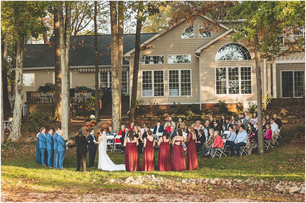 Large group of people gathered outside a residential building for a group photo shoot on a sunny day.