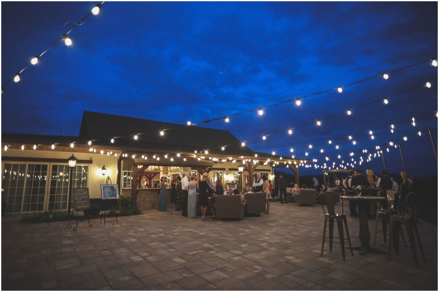 String lights illuminate an outdoor venue at dusk with a deep blue sky creating a magical evening atmosphere.