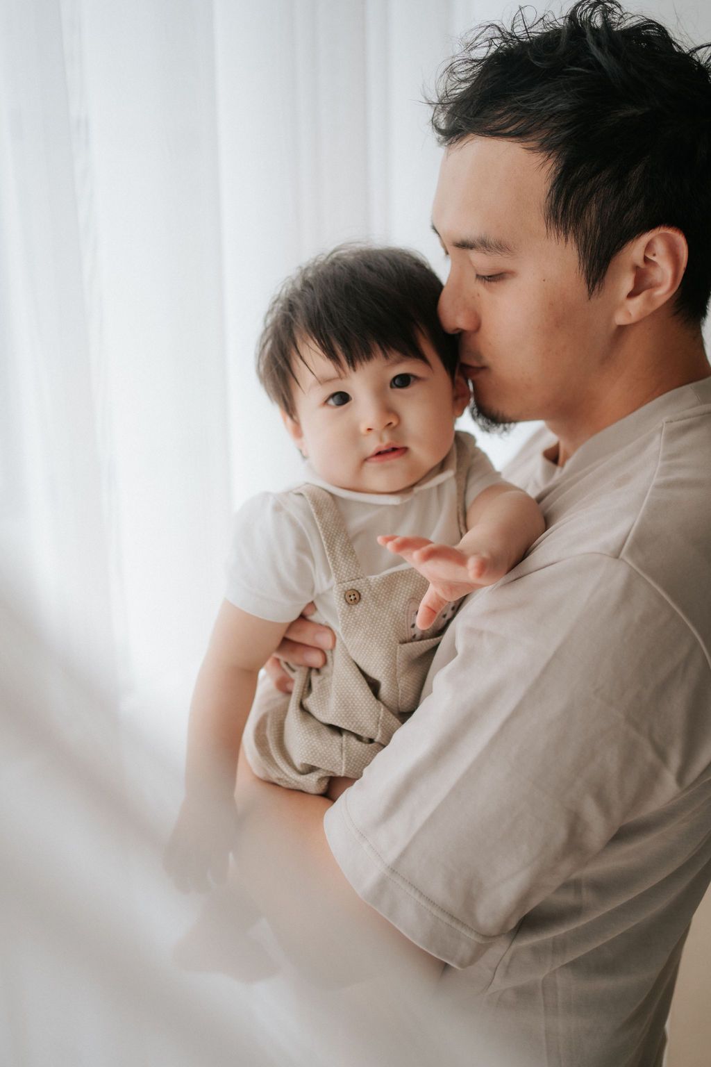 A parent and child share a joyful moment playing together in warm sunlight by a window.一位家長和孩子在溫暖的陽光下，於窗邊玩耍，享受著快樂的時光。
