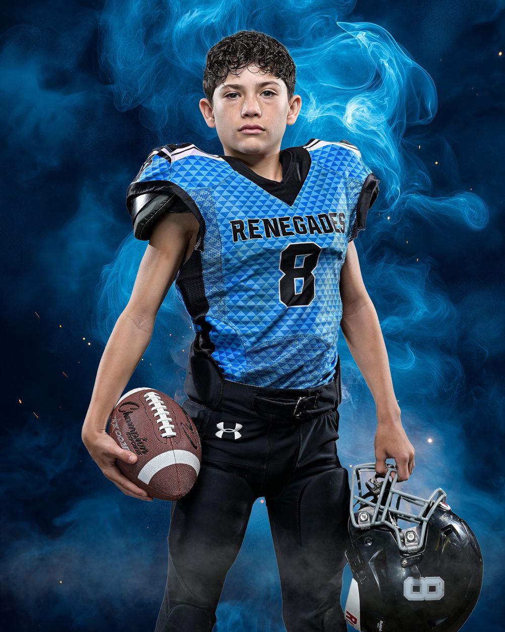 Youth football players in blue jerseys posing with equipment against smoky background.