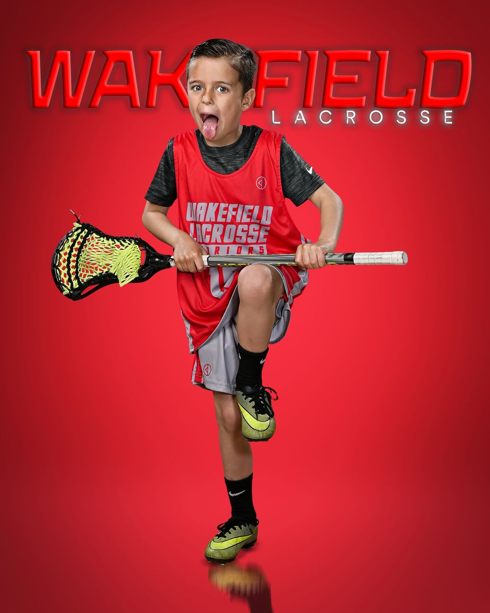 Young boy in Wakefield Lacrosse red jersey holds lacrosse stick, posing energetically on red background.
