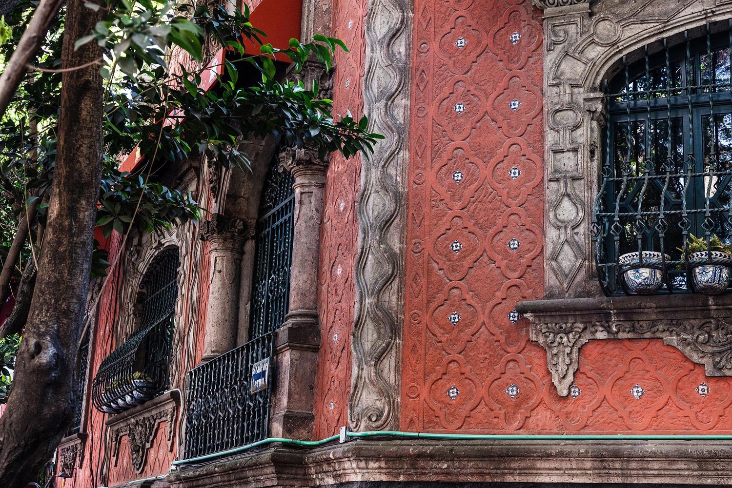 Ornate pink building facade with wrought iron balconies and decorative architectural details in a historic style.