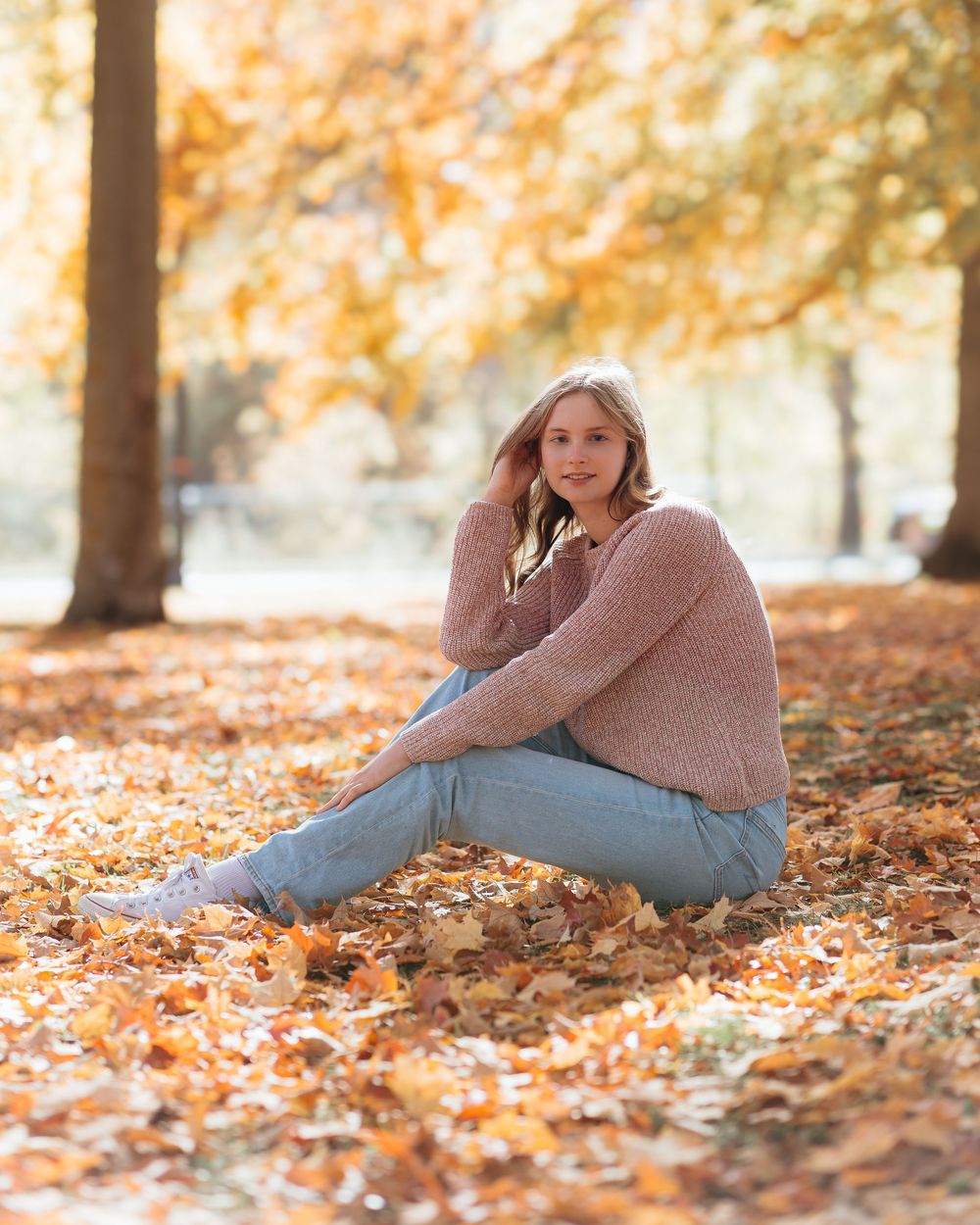 Portrait series of senior girl in casual attire lounging in fallen autumn leaves. Senior photographer in central Michigan. Fall photos.