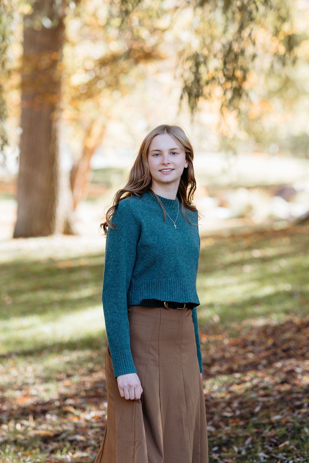 A series of outdoor portrait photos showing young woman senior in a teal sweater and brown skirt among autumn trees. Senior session photos.