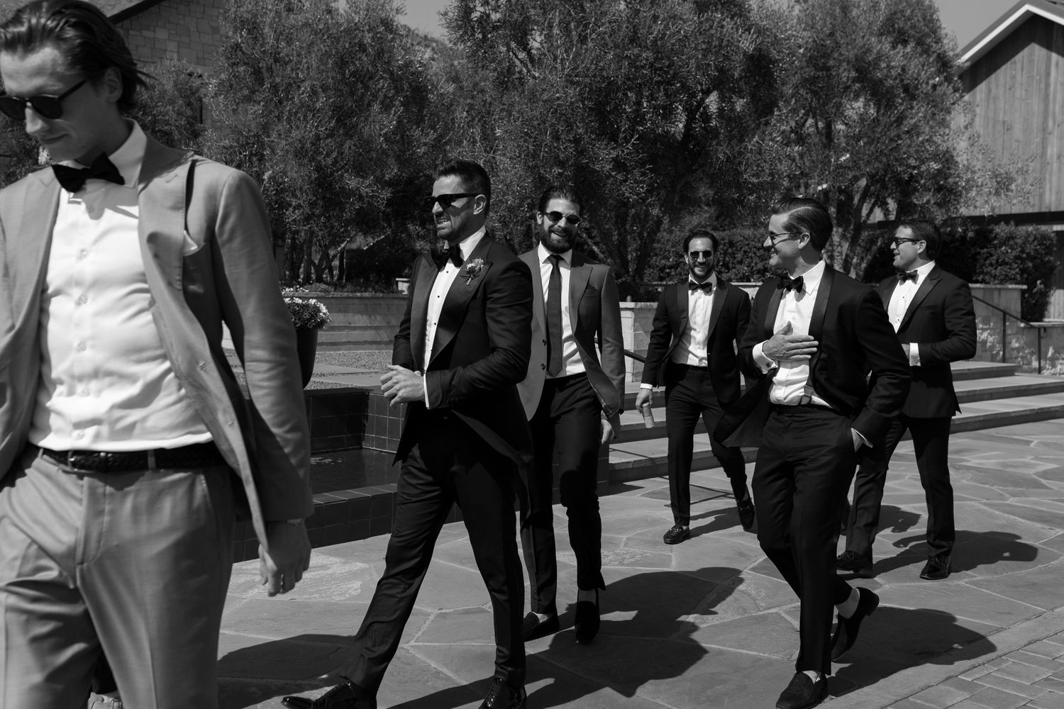Groomsmen in formal attire walking together in classic black and white photography.