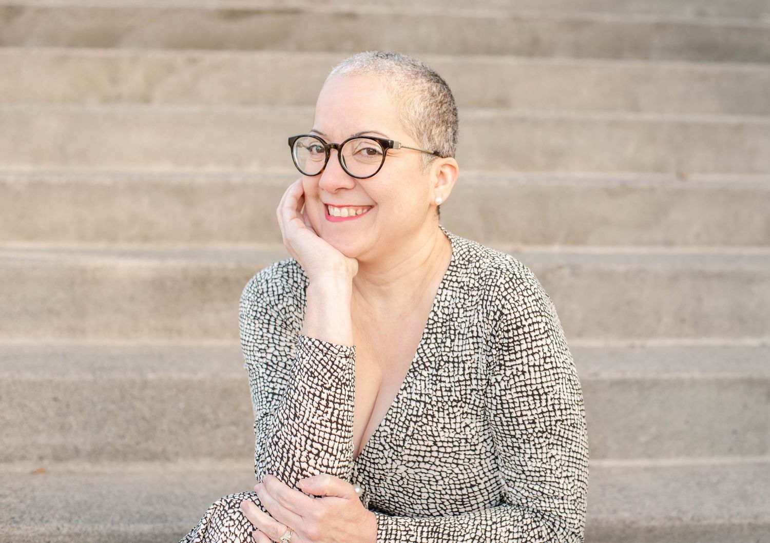 Portrait session on concrete steps features someone in a patterned outfit and glasses.