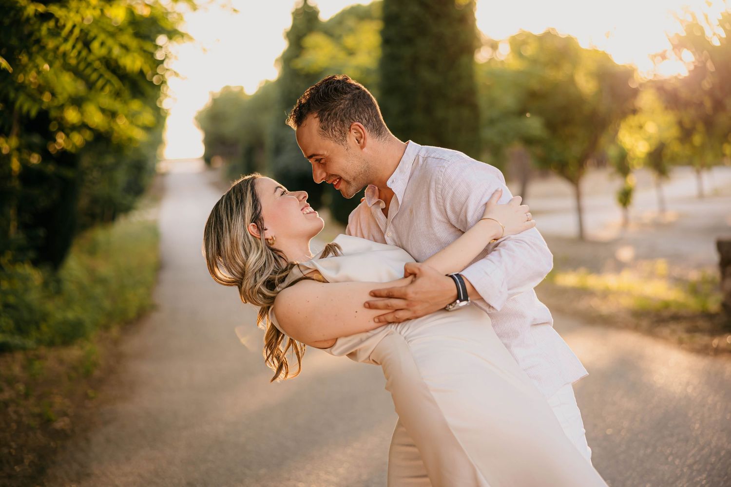 Fotografía de pareja al atardecer donde se miran sonriendo a punto de besarse