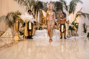 Egyptian-inspired fashion show on marble runway with palm trees and elaborate costumes.