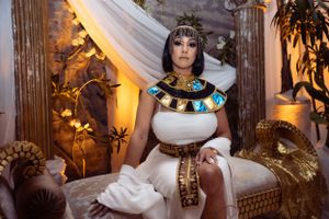 Ancient Egyptian themed party setup with ornate decor featuring white drapes, gold accents, and atmospheric lighting.