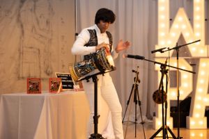 Performer with accordion entertaining guests at themed party with illuminated backdrop.