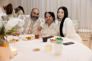 Guests enjoying a formal dinner event at a table with white decor and place settings.