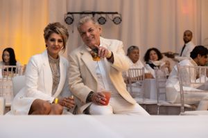 Guests in white attire seated at an elegant reception with warm lighting.