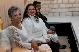 Group enjoying conversation at formal event with white stone wall backdrop.