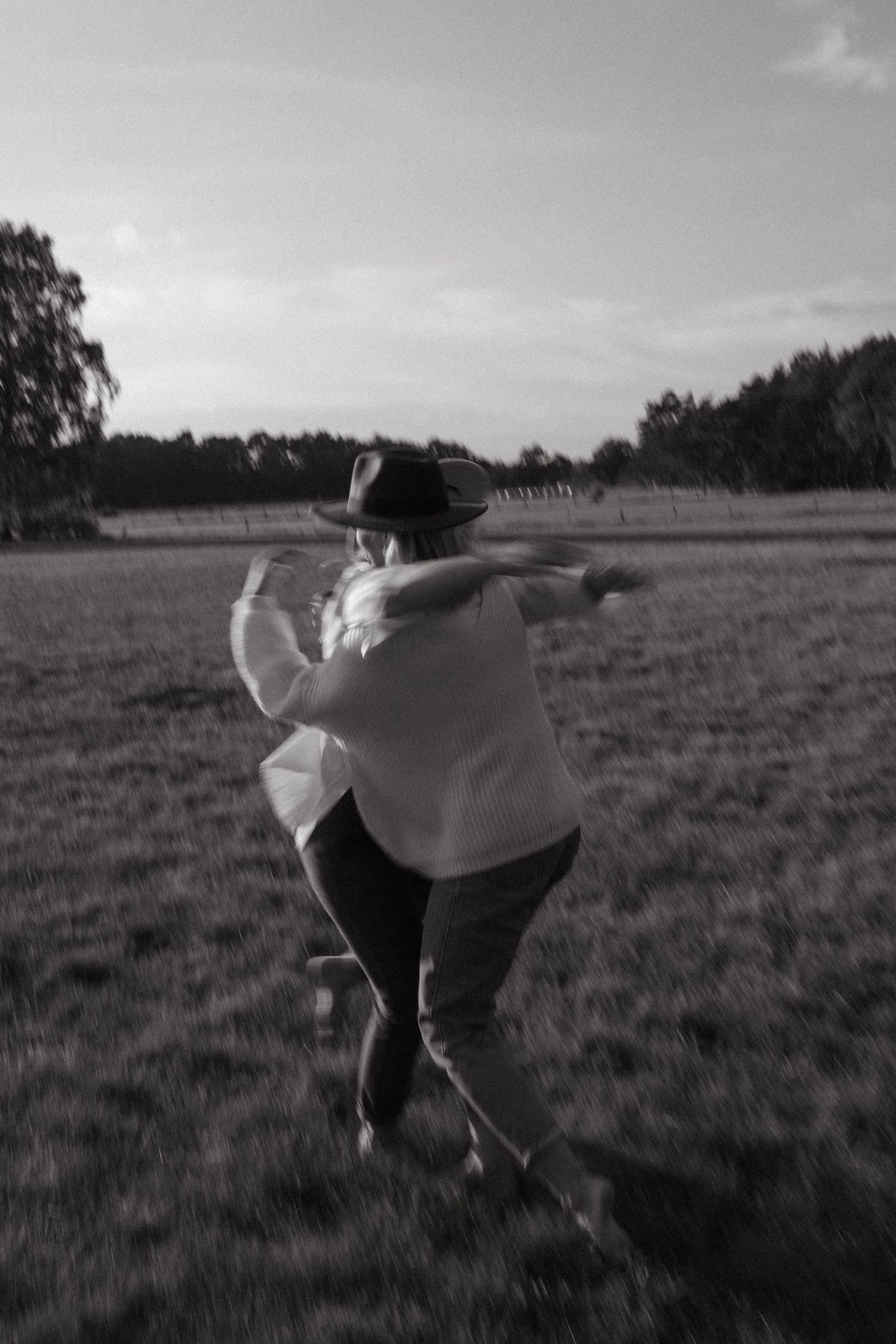 Black and white photos show a person twirling in an open field wearing flowing fabric.