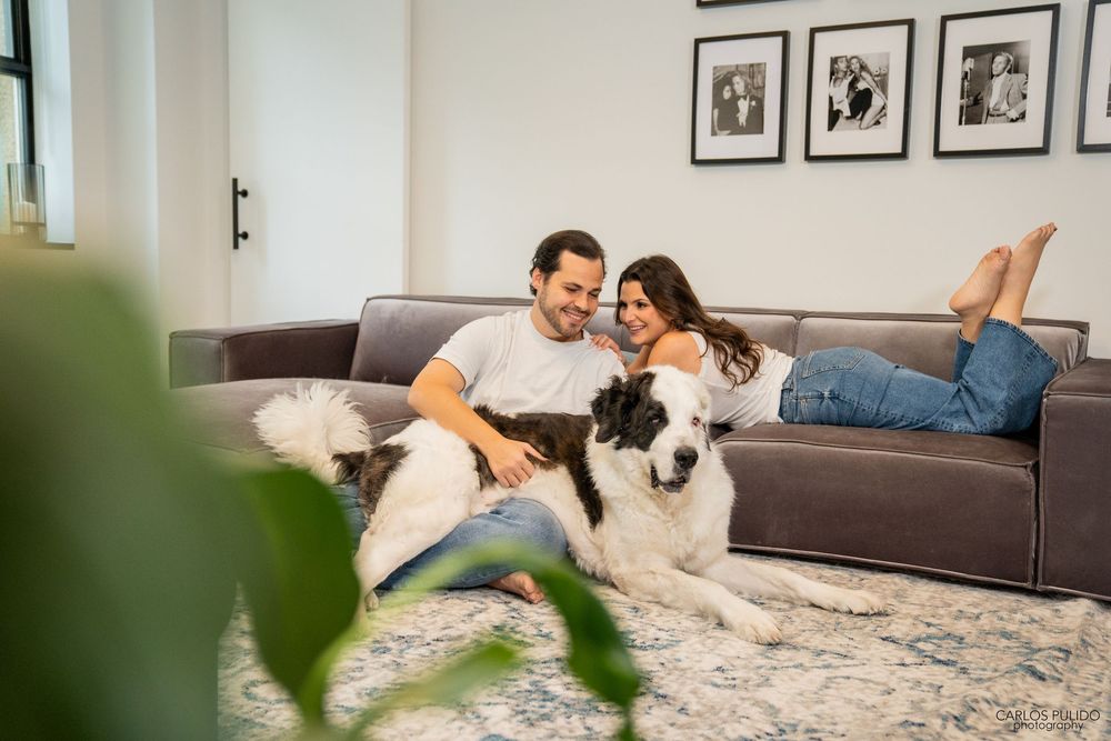 A couple relaxes together on a cozy gray couch at home while sharing an intimate moment.
