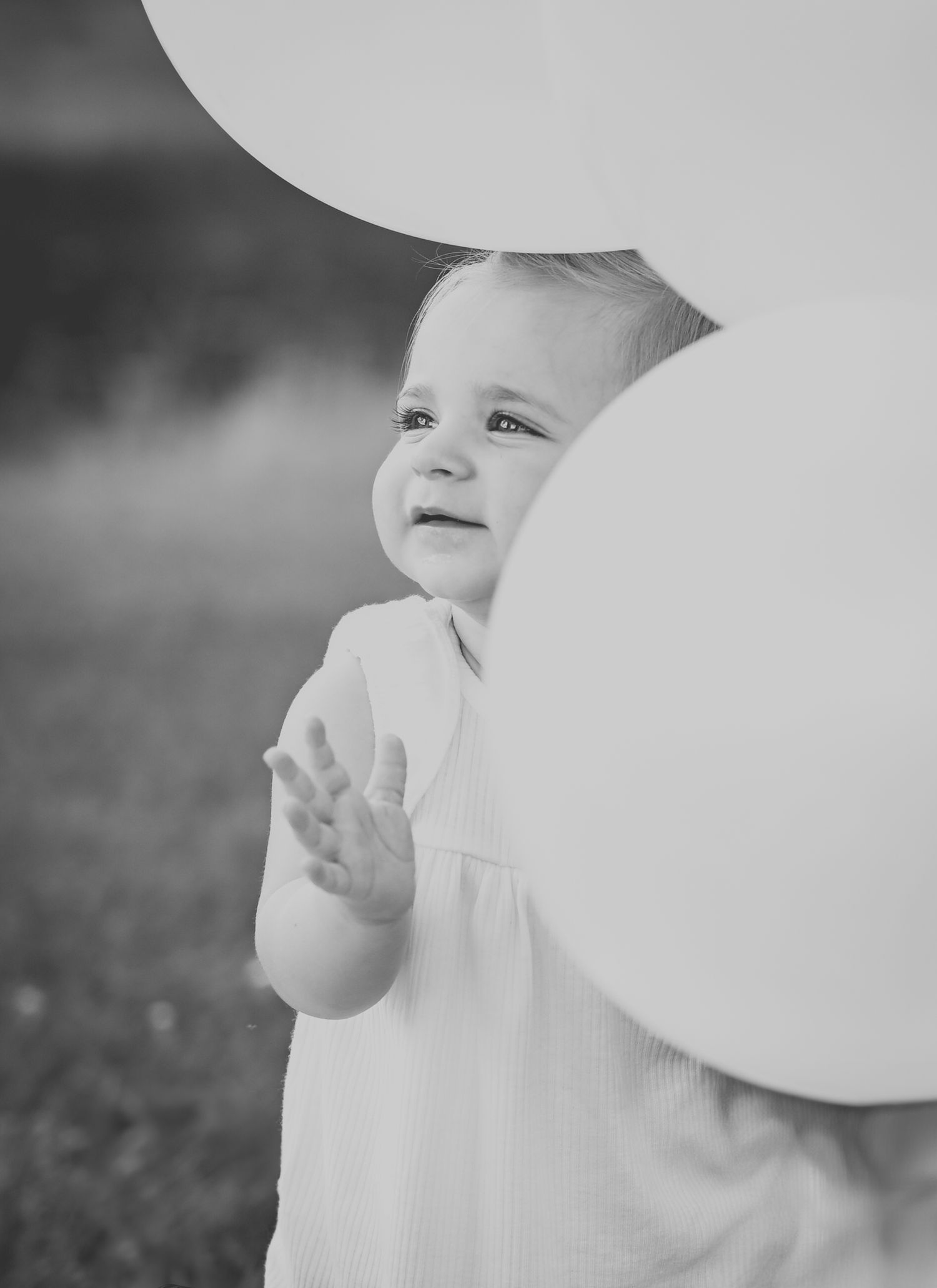 Baby girl with balloons on first birthday.