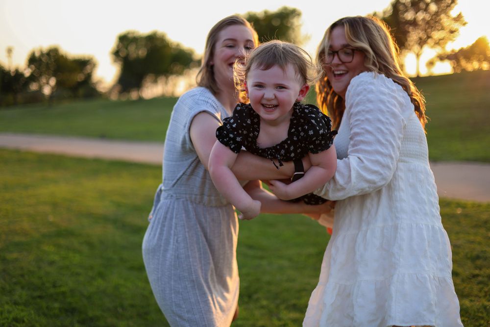 A joyful group hug captured in warm evening sunlight at the park.