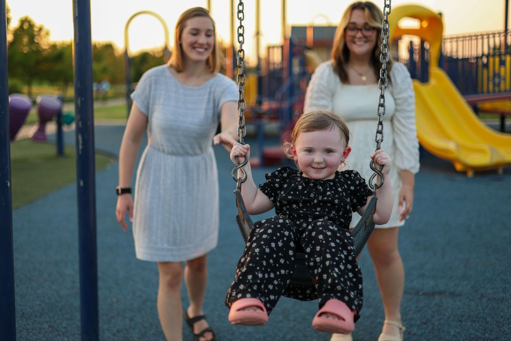 A fun moment at a playground with someone swinging while others watch and smile.
