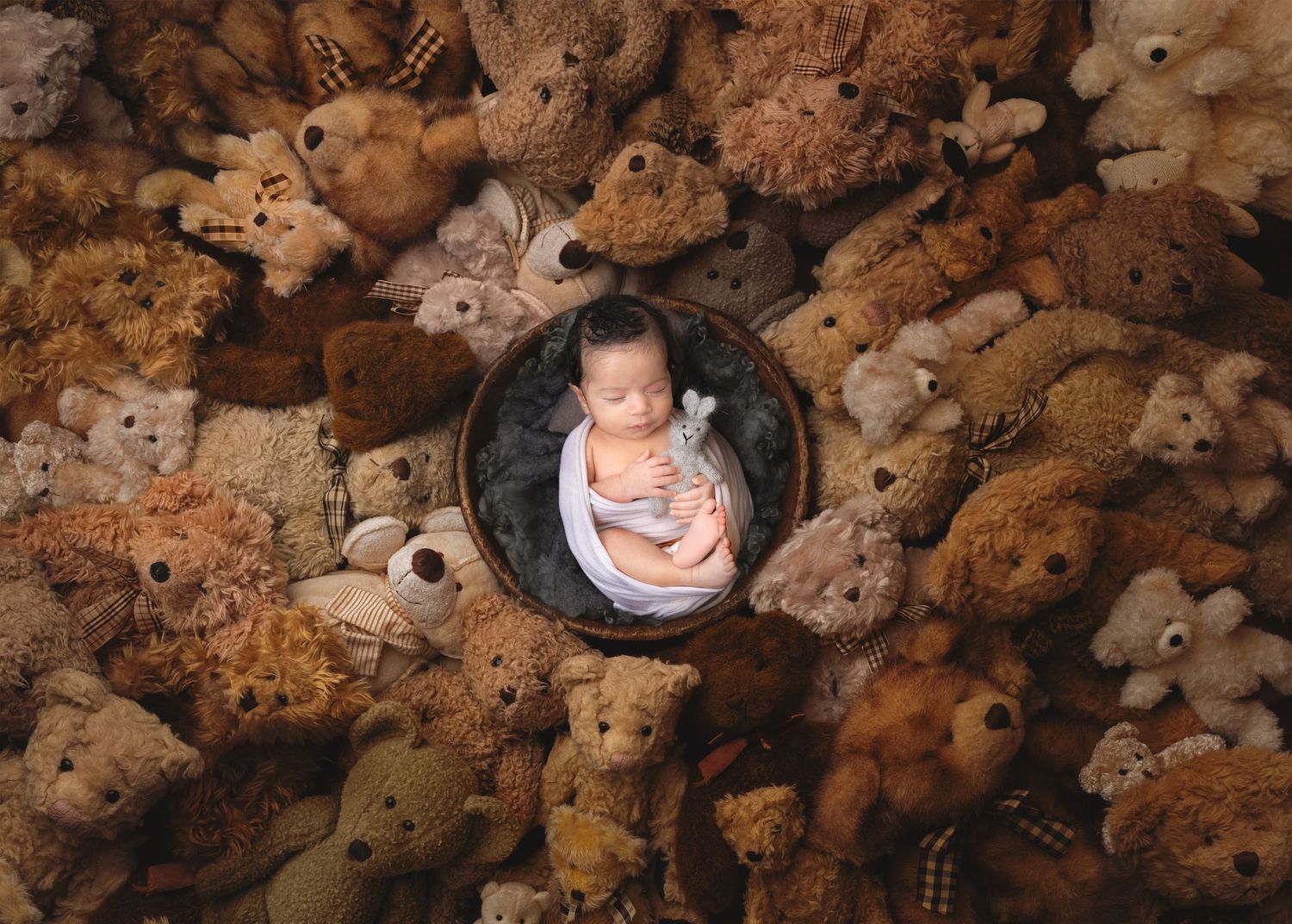Creative newborn photography with baby nestled in a circle surrounded by teddy bears.