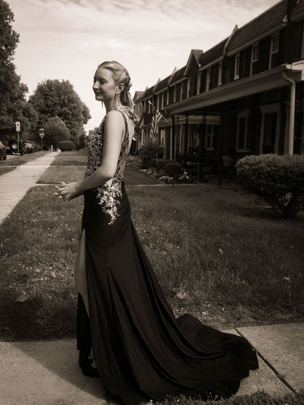 An elegant formal gown in black with a flowing train shown in a vintage-style sepia photograph.