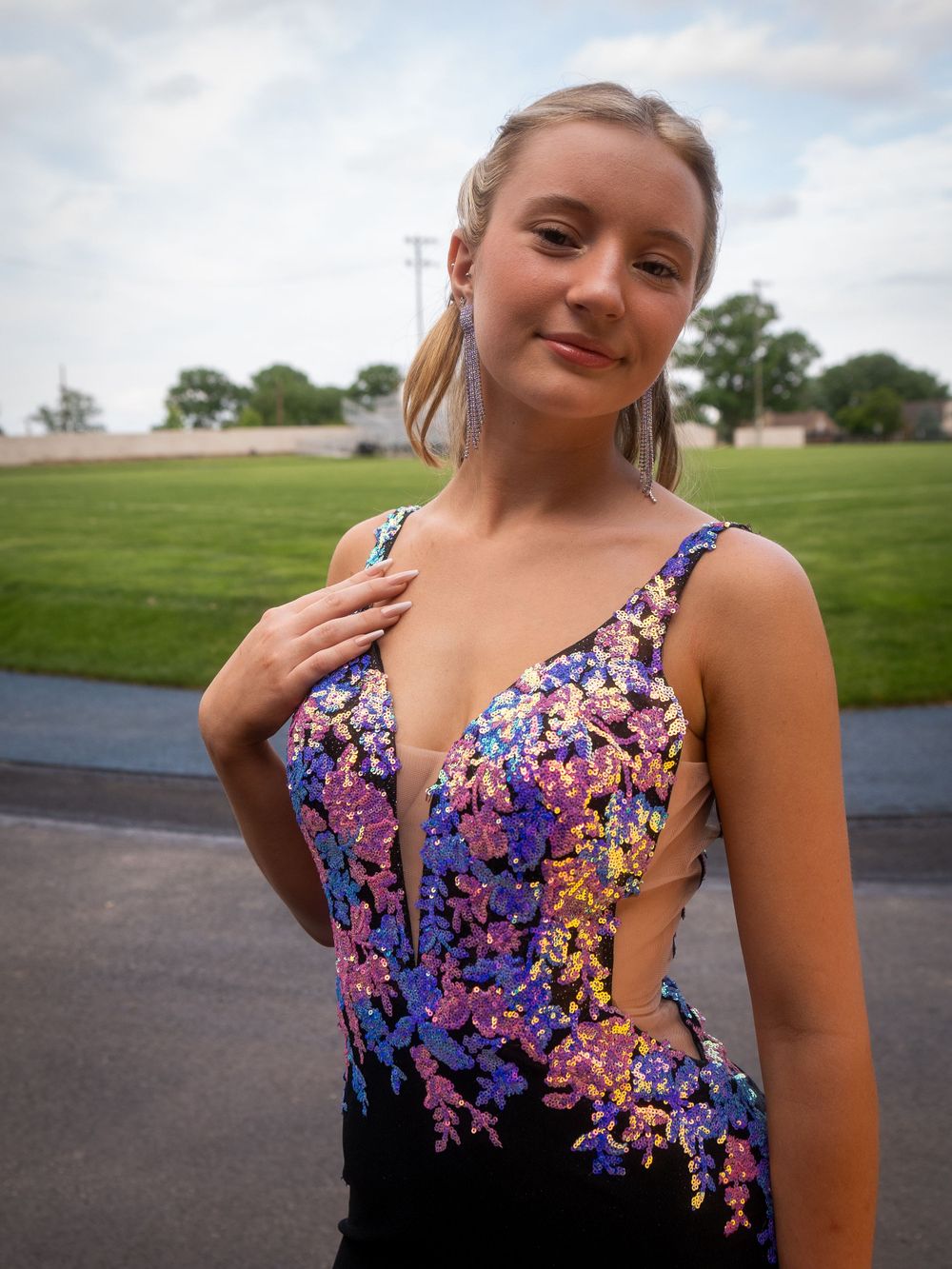 Formal dress with colorful floral beading on black fabric shown in an outdoor portrait.