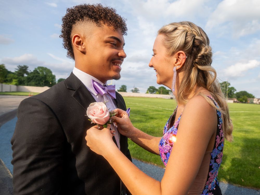 A couple shares a sweet moment while adjusting flowers during prom photos.