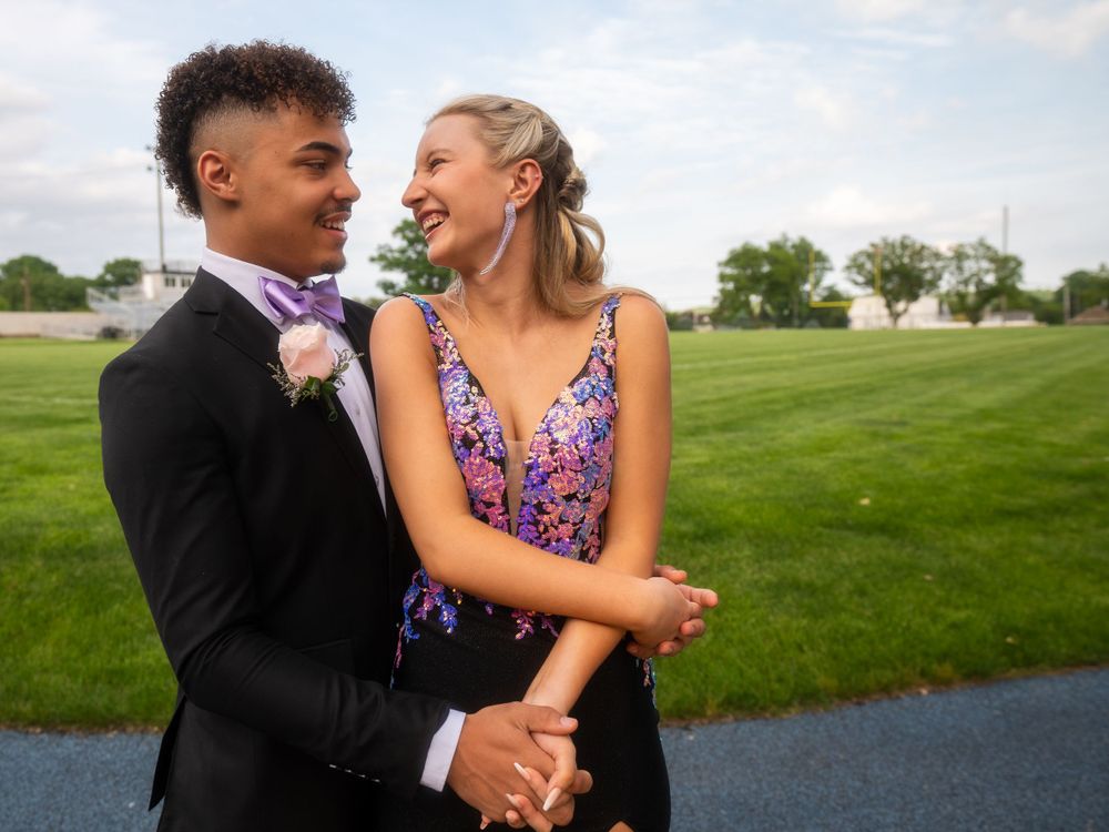 A couple laughs together during their prom photoshoot on a spring day.