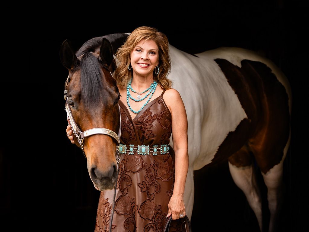 Horse portrait session against black background with rider in western attire.